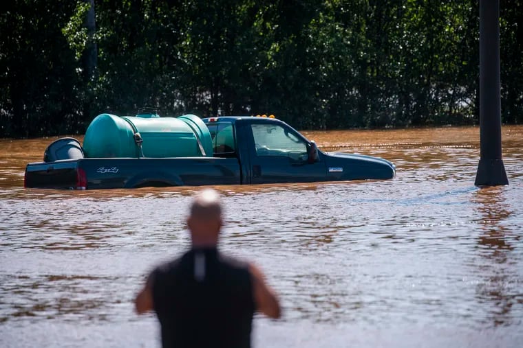 A man looks at a vehicle flooded on Sept. 2 as a result of the remnants of Hurricane Ida in a parking lot in Somerville, N.J.
