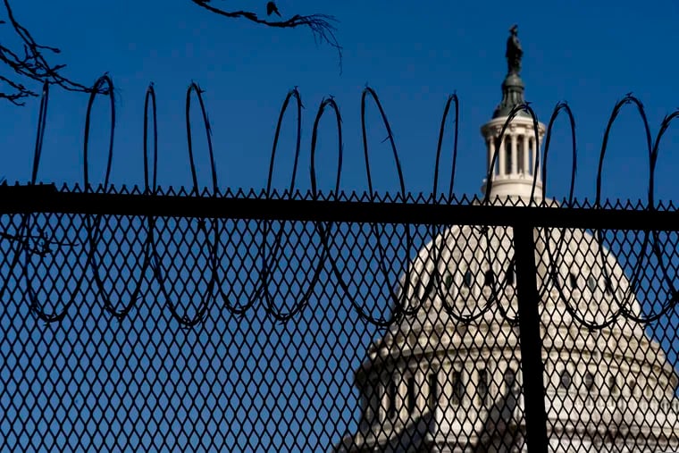 The Dome of the Capitol Building is visible through razor wire installed on top of fencing on Capitol Hill on Thursday.