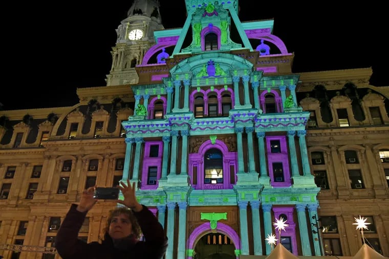 Visitors to Dilworth Park watch the premiere of the Deck the Hall Light Show illuminating City Hall in 2019.