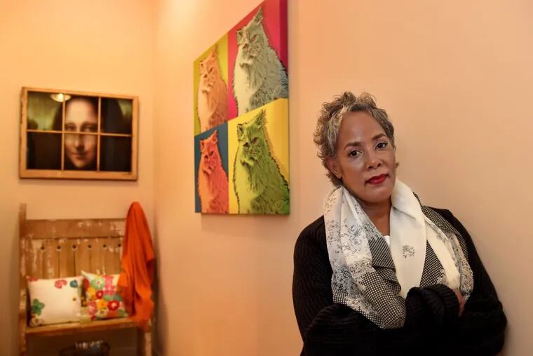 Mona Lisa Jackson,  former owner of now-closed lingerie boutique Coeur,  in her apartment, with a painting of her cat, Ferrari, in the background.