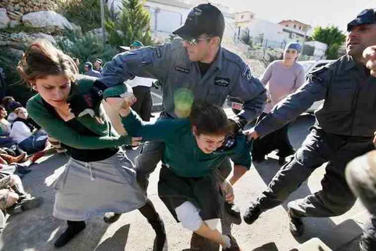 Israeli police haul away young protesters in the West Bank settlement of Kedumim. Police said the mostly teenage demonstrators pelted them with eggs to protest a construction freeze.