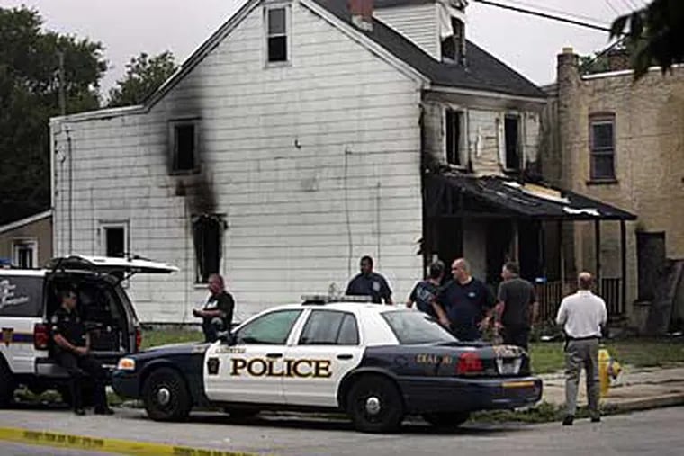 Crime Scene Investigators from the Chester Police Department examine a house where three people were killed in a fire late Sunday night. (Laurence Kesterson / Inquirer)