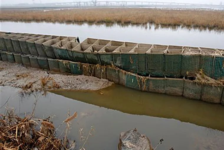 In this Dec. 8, 2012 photo, the battered and emptied Richard P. Kane Wetland Mitigation Bank, a long barrier wall made of large baskets filled with sand and dirt, runs through the Meadowlands in Moonachie, N.J. The barrier was built primarily to control the movement of tidewaters in and out of the wetlands area and not for flood protection. But since the tidal surge from Superstorm Sandy washed over it and damaged more than 2,000 homes and other buildings, attention has turned to what can be done to prevent similar river flooding in future storms. Unfortunately, however, no one seems to own the problem. (AP Photo/Mel Evans)