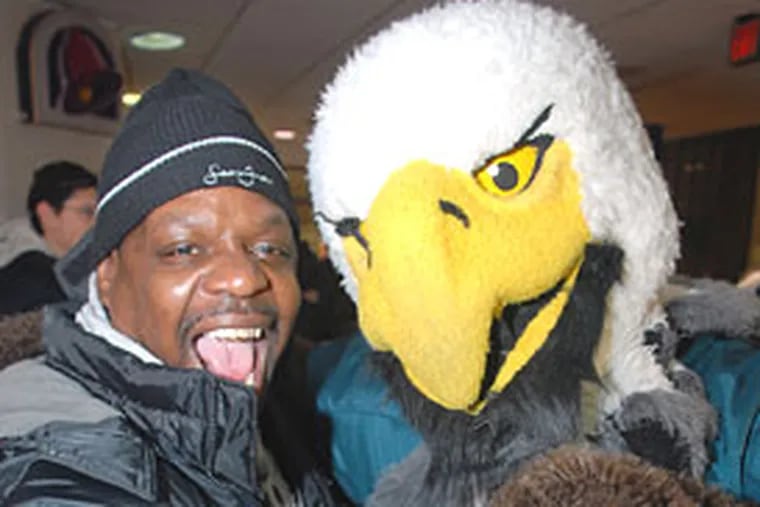 Hector Herrington of North Philadelphia takes a self-portrait with his cell phone with Eagle's mascot Swoop during a team rally in the Penn Center concourse this morning.