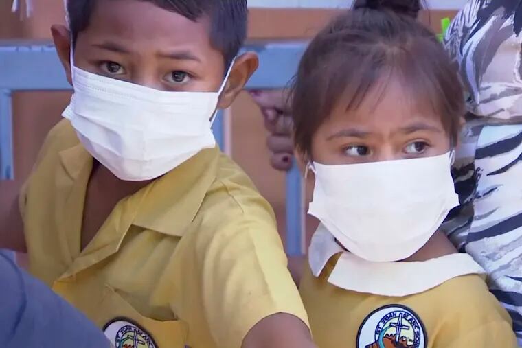 In this November 2019, image from video, masked children wait to get vaccinated at a health clinic in Apia, Samoa. Samoa closed all its schools on Monday, Nov.18, 2019, banned children from public gatherings and mandated that everybody get vaccinated after declaring an emergency due to a measles outbreak. For the past three weeks, the Pacific island nation of 200,000 people has been in the grip of a measles epidemic that has been exacerbated by low immunization rates. (TVNZ via AP)