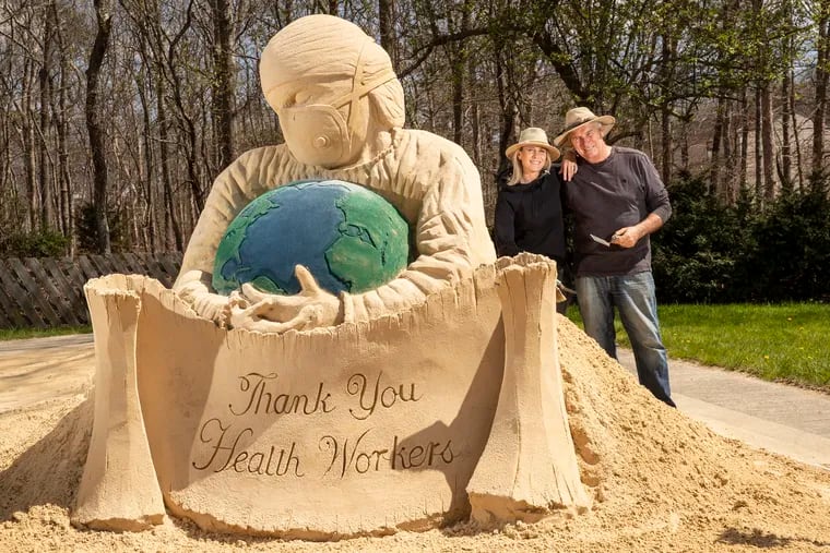 Artists John Gowdy, right, and Laura Cimador Gowdy, his wife, left, have used their quarantine time to create a 6-ton sand sculpture thanking health-care workers for their courage.