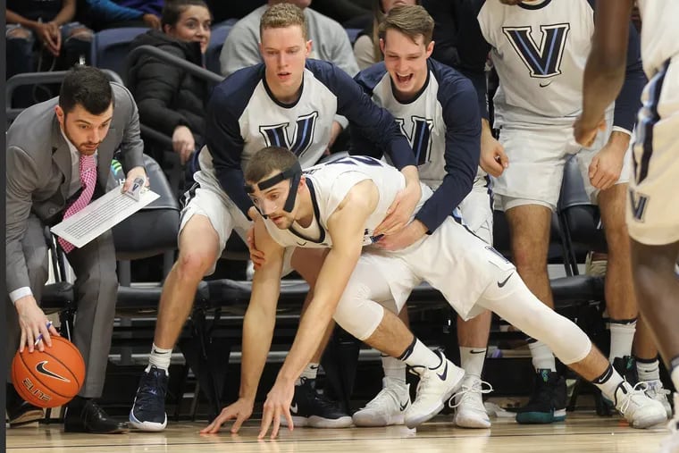Joe Cremo, bottom center, of Villanova is lifted up by Tim Saunders, left center, and Peyton Heck after diving after a loose ball during the 2nd half at Finneran Pavilion on Dec. 5, 2018.    CHARLES FOX / Staff Photographer