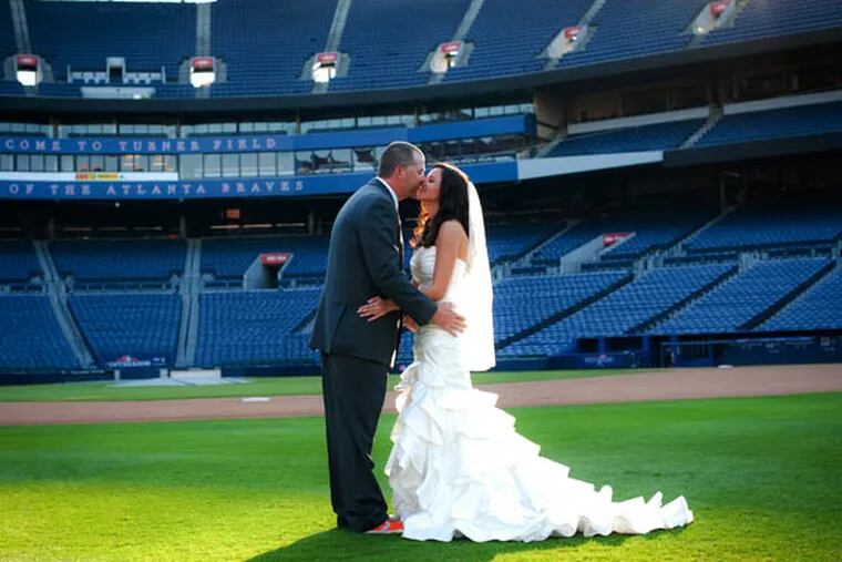 This Nov. 3, 2012 photo released courtesy of Trisha Benzine shows Nick and Trisha Benzine at their wedding held at Turner Field in Atlanta. Some couples, find that the massive stadiums where they enjoy hearing the crack of the bat can also be the perfect place to hear their beloved say, "I do." (AP Photo/Graceology Photography)