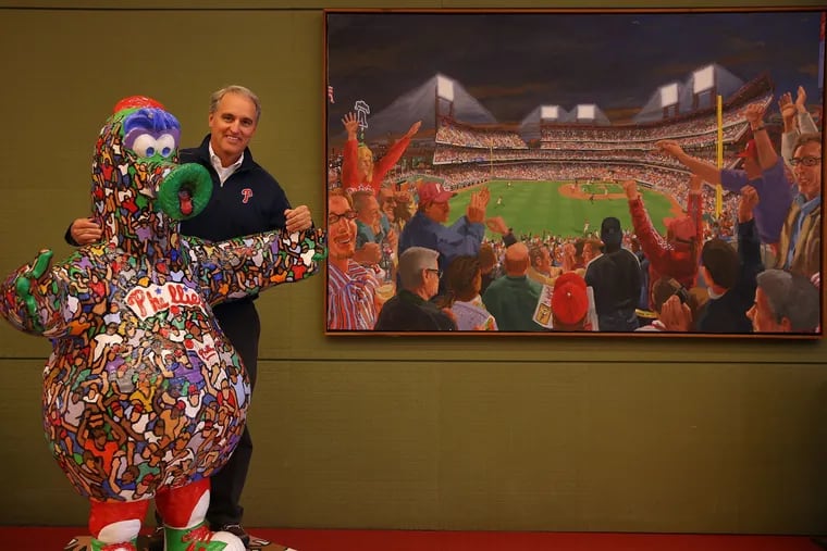 John Brasher, the Phillies director of Fun and Games, poses with a statue of the Phanatic inside Citizens Bank Park.