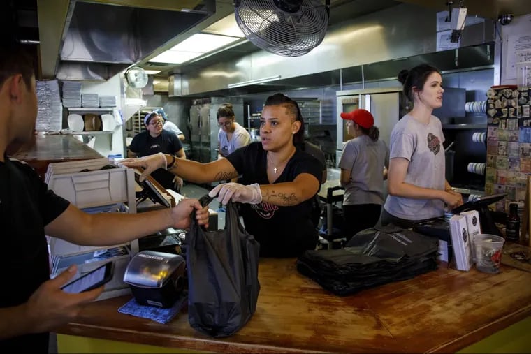 Aileen Nieves hands off a takeout order at Smoque BBQ in Irving Park for a lunch customer.