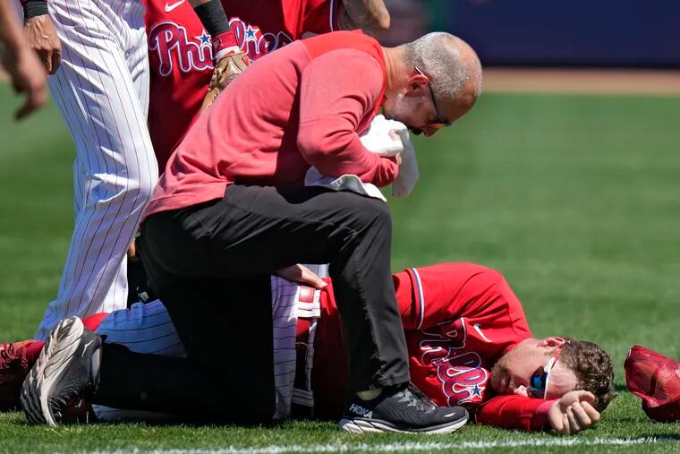 A trainer checks on Philadelphia Phillies first baseman Rhys Hoskins.