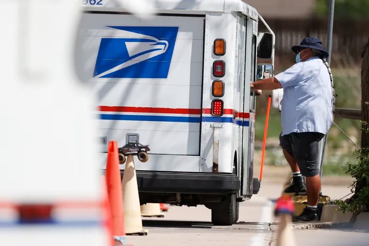 An instructor wears a face mask while directing a new hire on how to drive a delivery van at the U.S. Postal Service distribution facility, Friday, May 22, 2020, in east Denver.