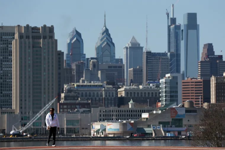 The Philadelphia skyline is visible in the background as a woman walks near the riverfront at Ulysses Wiggins Waterfront Park in Camden in February 2018.