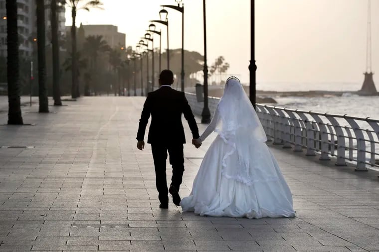 Lebanese groom Mostafa Baydoun, 29, walks with his bride Miran, 25, as they celebrate their wedding alone along the waterfront promenade in Beirut, Lebanon, Monday, April 6, 2020. The government has imposed a curfew to help stem the spread of the coronavirus. (AP Photo/Hussein Malla)
