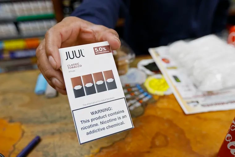 A cashier displays a packet of tobacco-flavored Juul pods at a store in San Francisco on June 17, 2019. San Francisco supervisors are considering whether to move the city toward becoming the first in the United States to ban all sales of electronic cigarettes in an effort to crack down on youth vaping. The plan would ban the sale and distribution of e-cigarettes, as well as prohibit e-cigarette manufacturing on city property. Business owners say it would hurt their businesses.
