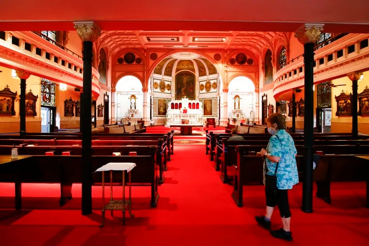 A parishioner enters St. Michael Roman Catholic Church on Sunday. The Rev. Arturo Chagala made major changes to church's interior — ripping out wooden pews and altar rails and covering the marble floors in bright red carpeting — without consulting parishioners or the Archdiocese.