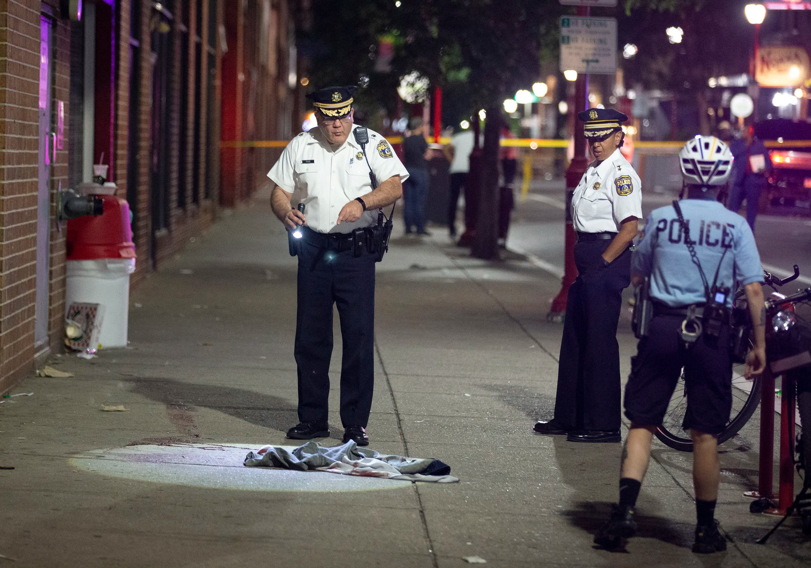 Philadelphia Police D. F. Pace looks over evidence at the scene of a shooting on and near South Street that left 3 dead and 11 wounded.