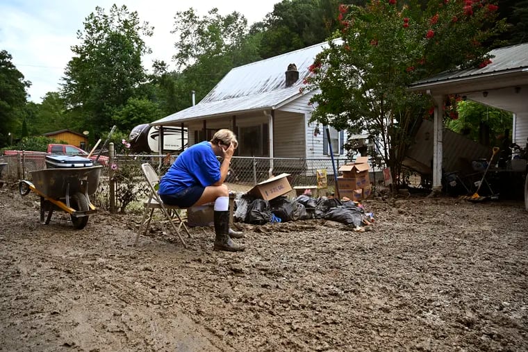 Teresa Reynolds sits exhausted as members of her community clean the debris from their flood ravaged homes at Ogden Hollar in Hindman, Ky., Saturday, July 30, 2022.