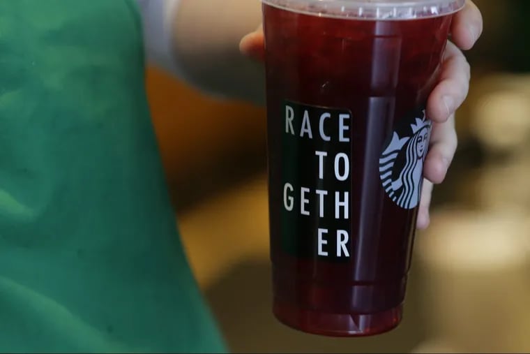A Starbucks barista holds an iced tea drink with a “Race Together” sticker on it at a Starbucks in 2015. Starbucks, trying to tamp down a racially charged uproar over the arrest of two black men at one of its stores in Philadelphia, plans to close more than 8,000 U.S. stores for several hours next month to conduct racial-bias training.
