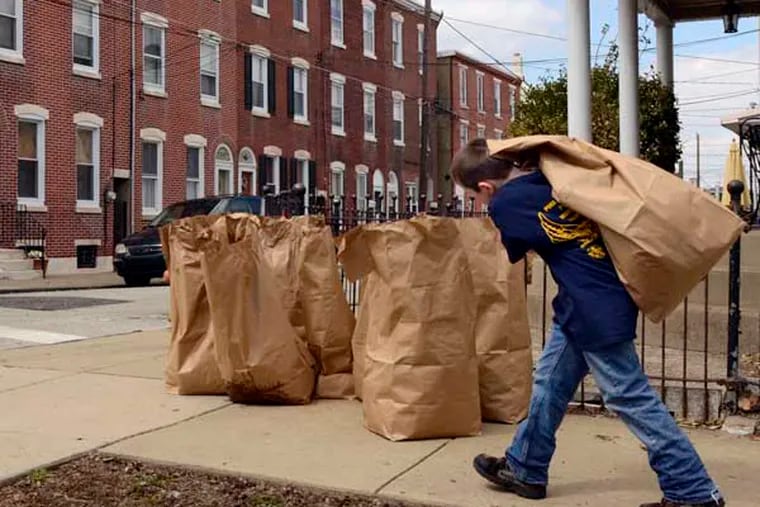 Ten year-old Ryan McCann hauls a bag of raked trash to the curb at Pratt and Salmon Streets in Bridesburg April 5, 2014, during the 7th Annual Philly Spring Cleanup, joining 19,737 volunteers picking up trash at 550 cleanup sites across the city.  ( TOM GRALISH / Staff Photographer )
