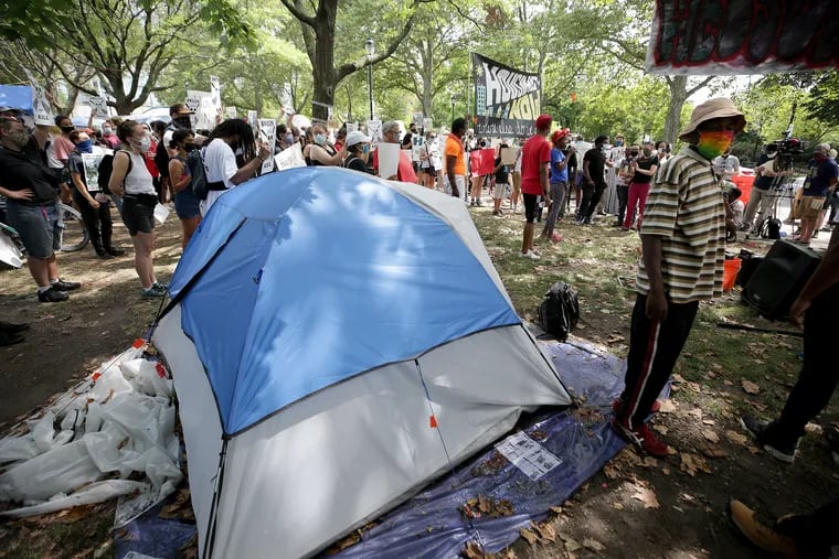 A crowd gathers during a press conference at a homeless encampment in a park on the Benjamin Franklin Parkway in 2020.