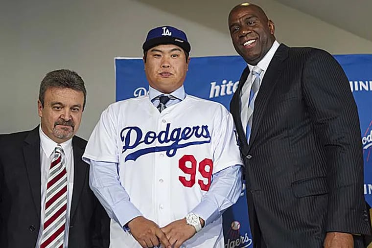 Los Angeles Dodgers general manager Ned Colletti, left, and co-owner Magic Johnson, right, present pitcher Ryu Hyun-Jin, center, of South Korea, during a baseball news conference (Damian Dovarganes/AP)