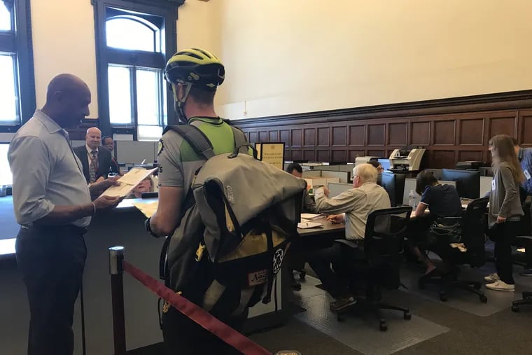 In a file photo, Tim Conheeney, a bike courier, waits in line at the First Judicial District's Civil Filing Center in Room 296 of Philadelphia City Hall on Wednesday, May 29, 2019. He has been contacted more frequently by law firms to file civil documents in person in City Hall since the city court system's eFiling and other computer systems were shut down after a virus attack.
