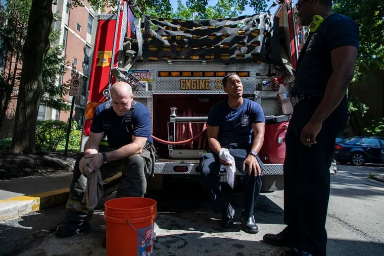 A firefighter and an EMT cool off after  helping the elderly move out of a Mount Airy apartment building that had lost power last July. The residents were moved to air-conditioned shelter. Responses to heat wave this summer could be complicated by the coronavirus concerns.