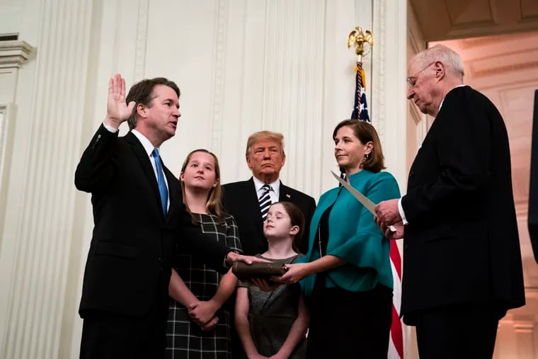 President Donald Trump watches as his second successful nominee to the high court, Brett Kavanaugh, left, is sworn in by retired Justice Anthony Kennedy at the White House in October 2018.