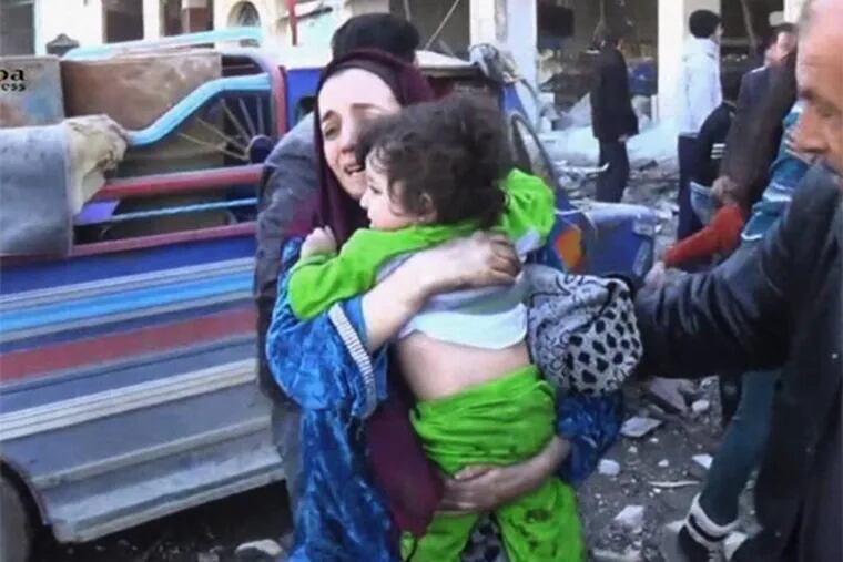 In this image taken from video obtained from the Shaam News Network, which has been authenticated based on its contents and other AP reporting, a woman carries a child out of a building after a blast at the building in Aleppo, Syria. (AP Photo/Shaam News Network via AP Video)