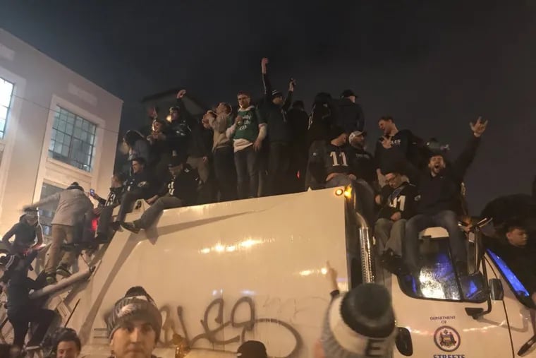 Revelers mount a Streets Department truck parked along Broad and Pine streets after the Eagles’ Super Bowl victory.