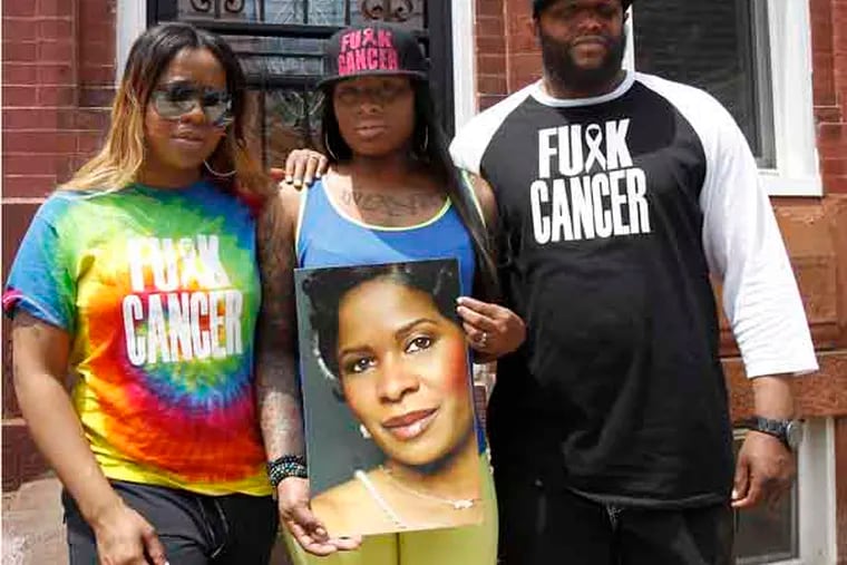 Makia Underwood, left, and her sister Zakia Clark, center, along with their uncle Curran Underwood, right, wear their anti-cancer gear in Philadelphia on May 21, 2013. Last Sunday they were escorted from the King of Prussia mall because because they were told the message was offensive. Makia and Zakia's mother recently lost her battle with cancer. Curran was not wearing the cap or shirt when he was in the mall. ( DAVID MAIALETTI / Staff Photographer )
