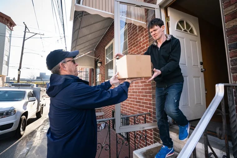 Robert Saxon (left) director of External Affairs for MANNA, makes an emergency food delivery to client Michael Olsen in South Philadelphia on Monday. MANNA brings food to home-bound individuals with life-threatening illnesses.