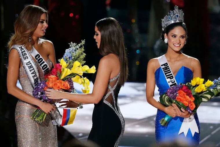 Former Miss Universe Paulina Vega (center), takes the flowers and sash from a tearful Miss Colombia, Ariadna Gutierrez.