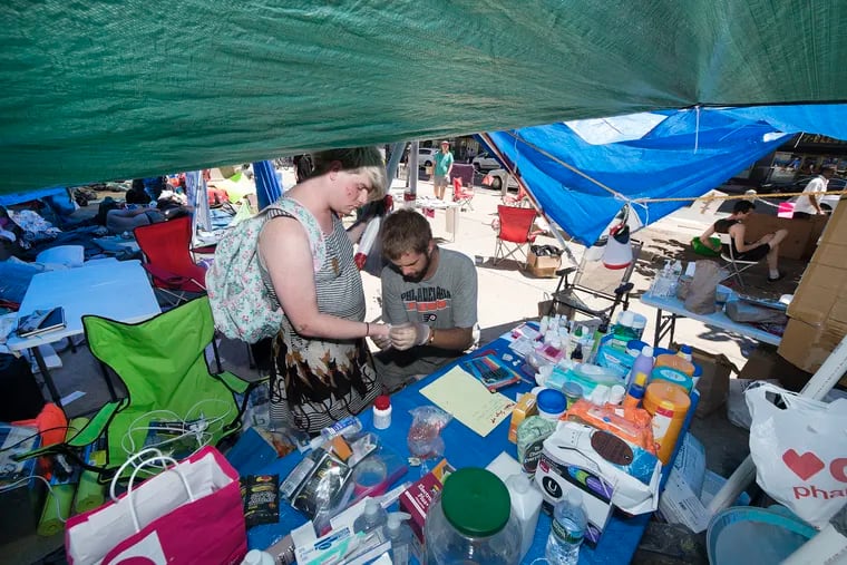 Former Firefighter, Nick Reed, right, disinfects a wound for Emily Reed at the sanitation tent in the ICE camp at City Hall, Philadelphia.