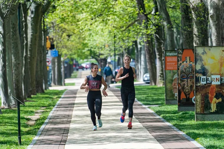 Two women run without masks along the Benjamin Franklin Parkway.