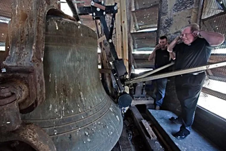 Fr. James A. Lyons (right), and John Woods, maintenance man for St. John the Baptist, cover their ears as the church bell chimes three times to mark 3 p.m. (File Photo / Staff)