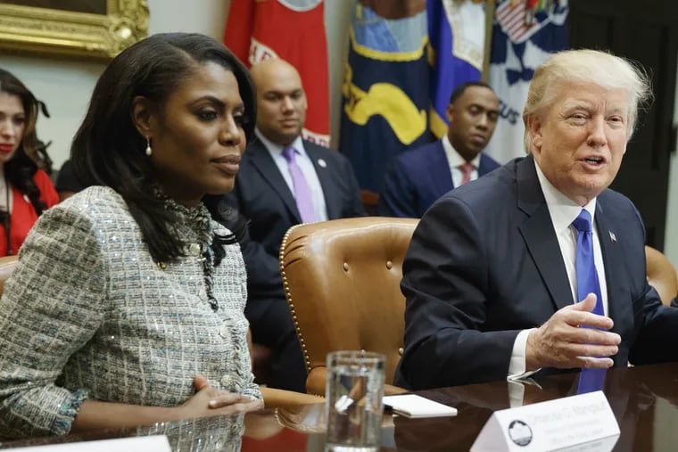 FILE – In this Feb. 1, 2017, file photo, President Donald Trump sits next to former White House staffer Omarosa Manigault Newman as he speaks during a meeting on African American History Month in the Roosevelt Room of the White House in Washington.