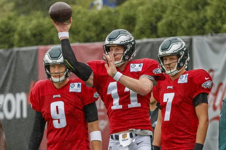 Philadelphia Eagle quarterback Carson Wentz, center, completes a pass to a running back, while quarterbacks, Nick Foles, left, and Nate Sudfel, right, wait their turn to complete the offensive drill during practice on Sunday August 19, 2018. MICHAEL BRYANT / Staff Photographer