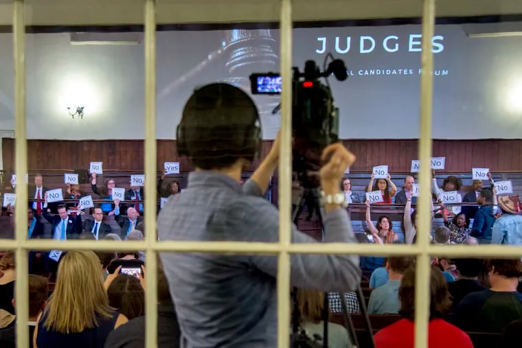 A coalition of partners in the Judge Accountability Table seeking to push judges toward criminal-justice reform hold a "Judge the Judges: Candidates Forum" at the Friends Center on Monday. The judicial candidates hold up signs — "Yes" or "No" — indicating their agreement on various questions pertaining to justice reform.