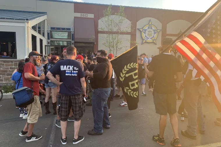 A man carrying a Proud Boys flag stands in the parking lot outside the "Back the Blue" party hosted by Lodge 5 of the Fraternal Order of Police after a visit to its headquarters by Vice President Mike Pence.