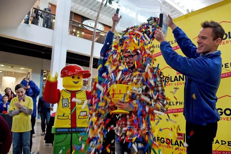 Michael Nieves, 29, of Monmouth Junction, N.J. is doused with a shower of Lego blocks  after winning the Brick Factor, a competition December 11, 2016 to find the next Master Builder for the coming-this-spring LEGOLAND Discovery Center at Plymouth Meeting Mall. Bertie, the LEGOLAND Discovery Center mascot, is at left.