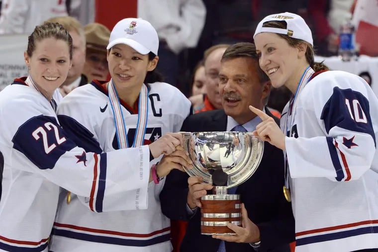 In this April 9, 2013, file photo, United States' Kacey Bellamy, Julie Chu and Meghan Duggan, from left, stand with IIHF president Rene Fasel as they are presented with the trophy after the U.S. team defeated Canada 3-2 in the gold medal game at the women's ice hockey world championships in Ottawa, Ontario. The governing body previously canceled the women’s world hockey championships set to be held in Canada and the men’s Under-18 championship to be played in Michigan next month.