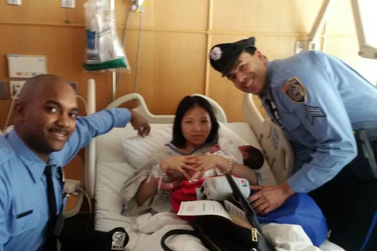SEPTA police officers Darrell James and Sgt. Daniel Caban with new mother and baby. The mother's name is Yanjin Li. The baby's name is Chris.