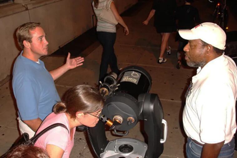 Derrick Pitts (right), chief astronomer at the Franklin Institute, conducts sidewalk astronomy with passersby at 2nd and Chestnut Streets, on a recent Saturday. (Source: Franklin Institute)