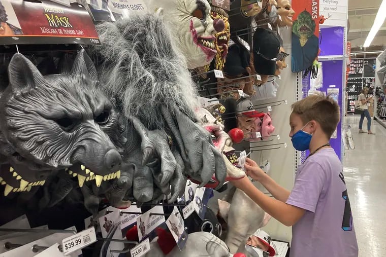 A young customer looks at a Halloween mask at a Party City store, Oct. 6, 2021, in Miami. Backed-up supply chains, combined with booming demand from shoppers, drove the U.S. consumer price index up 7% in December from a year earlier. (AP Photo/Marta Lavandier)