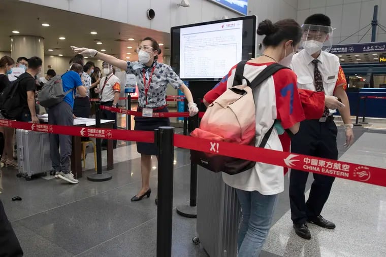 Airline employees redirect a traveller at a checkpoint for passengers from high-risk areas to present their COVID-19 test results before checking in for their flight at the Beijing Capital Airport terminal 2 in Beijing on Wednesday.