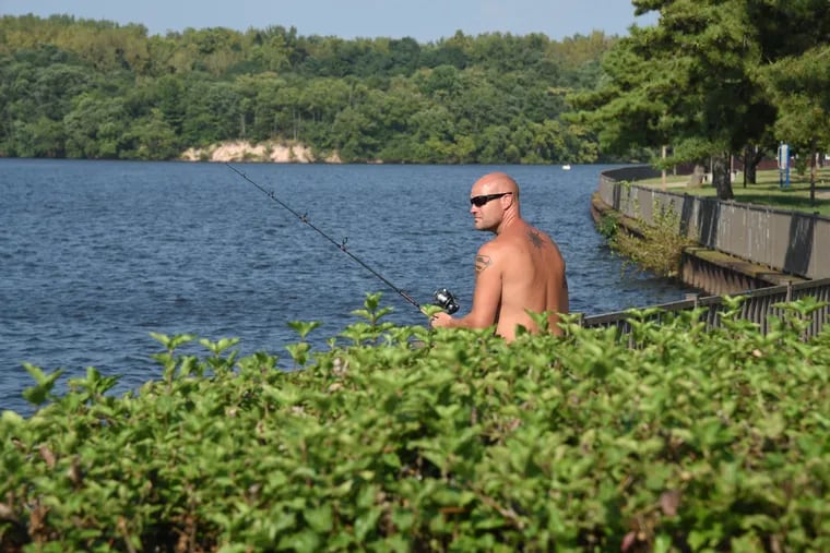 Chris Ent leaves his shirt in his pickup as he cools down, fishing on a hot day off along the Delaware River in Burlington City on steamy Tuesday. TOM GRALISH / Staff Photographer