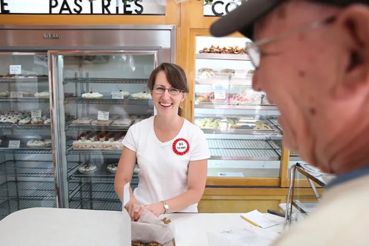 Jocelyn Wilson, left, smiles as she waits on longtime customer, Harry Beam, right, as Haegele's Bakery celebrates 85 years of business in the Mayfair section of Philadelphia on July 7, 2015. Wilson's grandmother worked at the shop. (DAVID MAIALETTI / Staff Photographer)