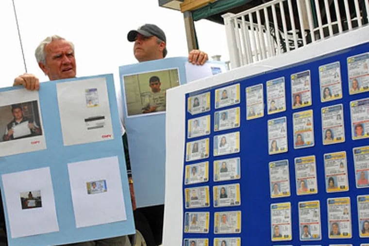 Jack Maley and Marc Antico hold mugshots of people found with fraudulent I.D.s in North Wildwood. (Tom Gralish / Staff Photographer)